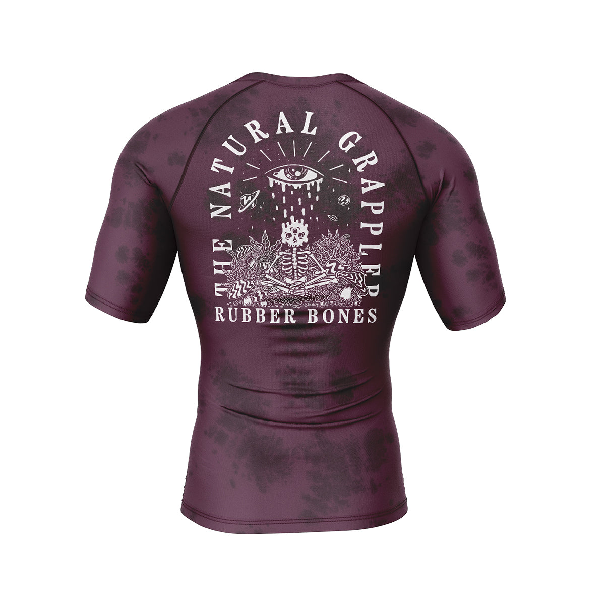 Maroon short-sleeve BJJ rash guard with a black tie-dye effect. Features a large white illustration of a skeleton surrounded by cosmic elements, with 'The Natural Grappler' and 'Rubber Bones' text arching over the design.