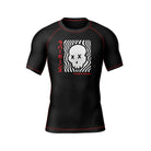 Black short-sleeve BJJ rash guard with red stitching and a bold front design. A stylized white skull with X eyes is set against a hypnotic black-and-white wave pattern, with Japanese katakana text reading 'Rubber Bones' in red for a striking contrast.