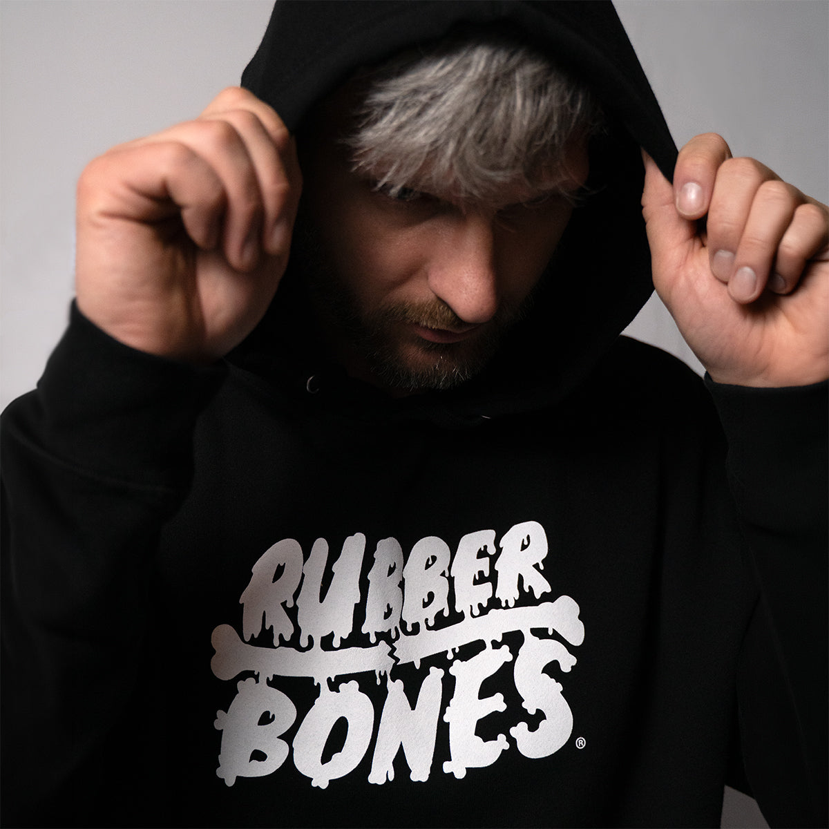 Man wearing black Rubber Bones logo hoodie with white skull branding prominently displayed on chest, showing fit and comfort for training or casual wear.