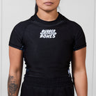 Model wearing the Women’s Ash BJJ Rash Guard featuring black body, white Rubber Bones logo, and gray marble side details.