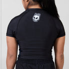Back view of the Women’s Ash BJJ Rash Guard showing black design with white melting skull Rubber Bones logo near neckline.