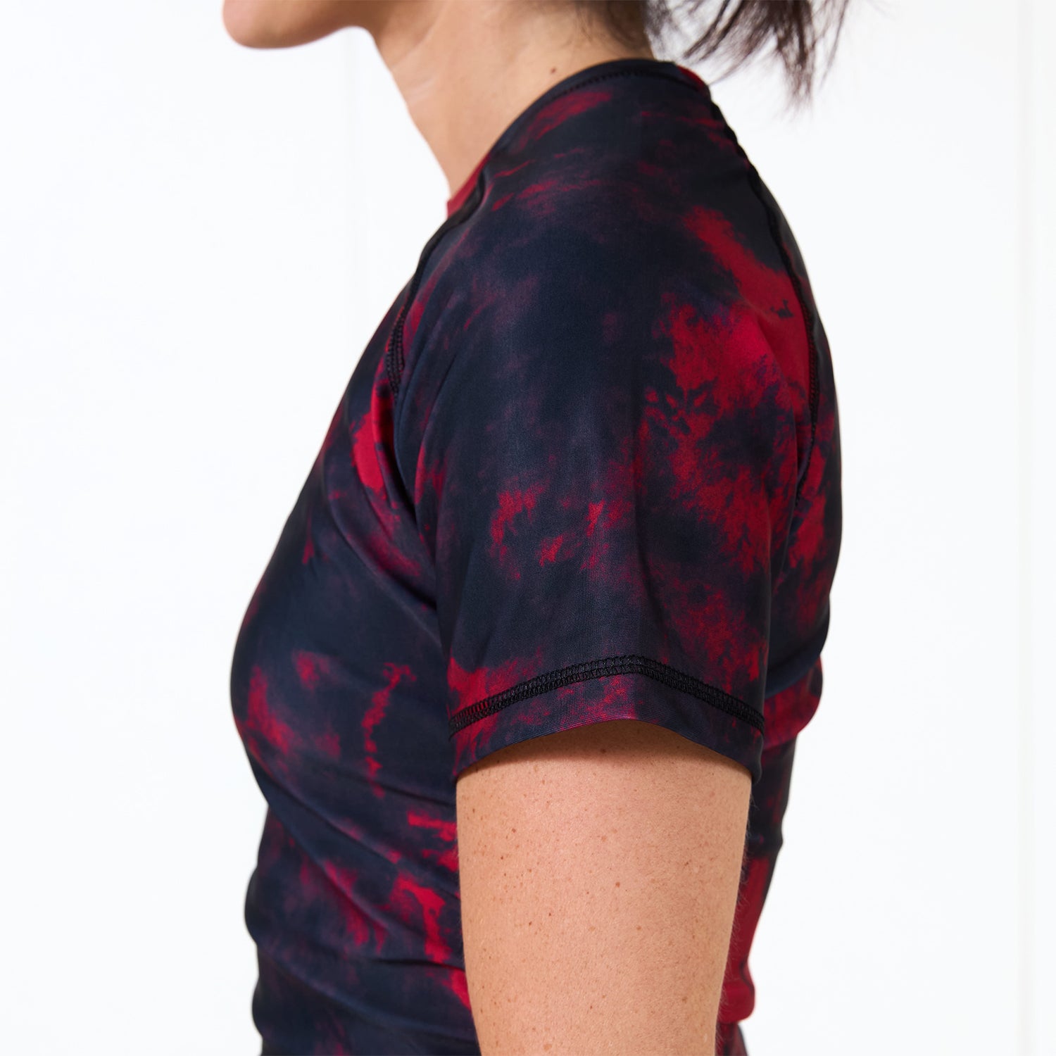 Side profile of the Women’s Ember BJJ Rash Guard highlighting the slim athletic fit and red-black colorway.