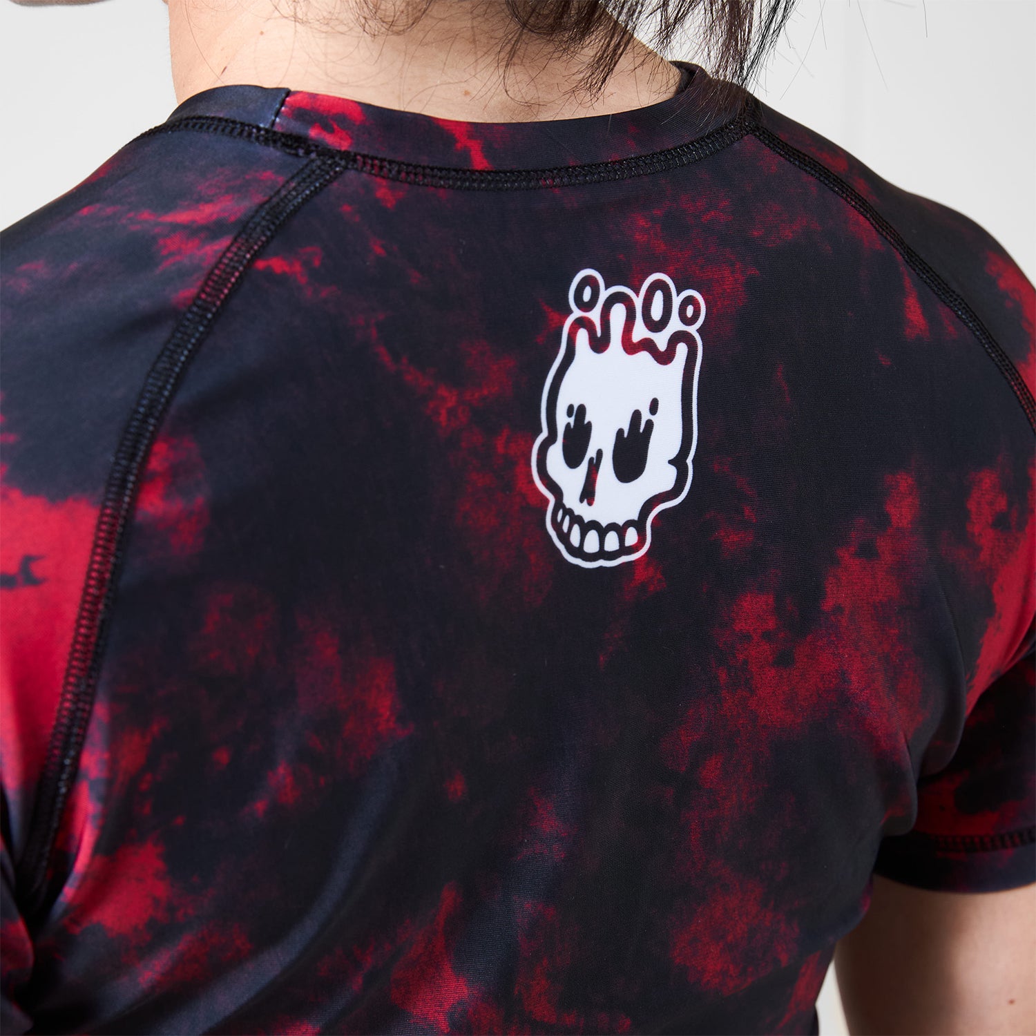 Close-up of melting skull Rubber Bones logo printed on the upper back of the Women’s Ember BJJ Rash Guard.