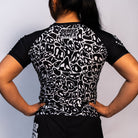 Back view of the Rubber Bones Ranked Black BJJ rash guard – Black compression rash guard featuring an all-over white skull pattern and Rubber Bones branding on the upper back.