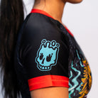 Close-up of the Rubber Bones Tora Oni women's rash guard sleeve – Teal melting skull graphic on a black background with red stitching.