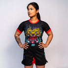 Athlete wearing the full Rubber Bones Tora Oni women's no-gi set – Black rash guard and shorts featuring a tiger-demon design, Japanese lettering, and red accents.